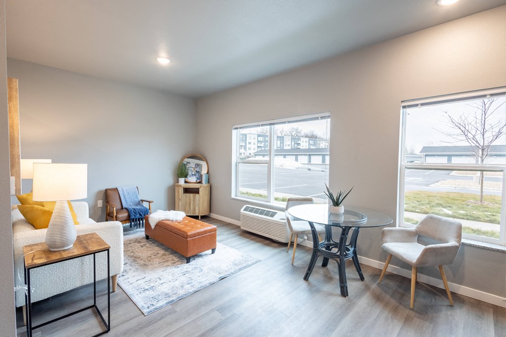 a living room with a table and chairs and a large window at Technology Park Apartments, Rochester, MN