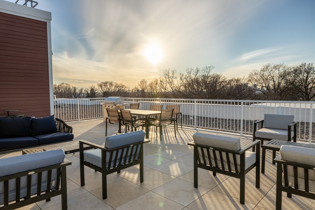 a patio with tables and chairs and a sunset in the background