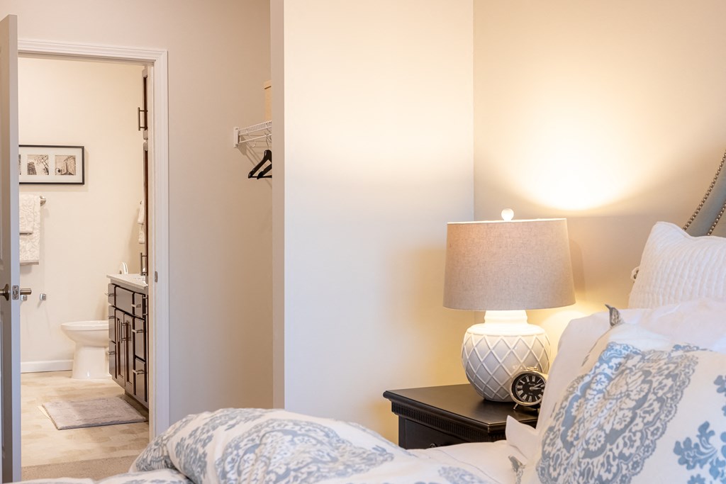 a bedroom with a bed and a lamp and a bathroom