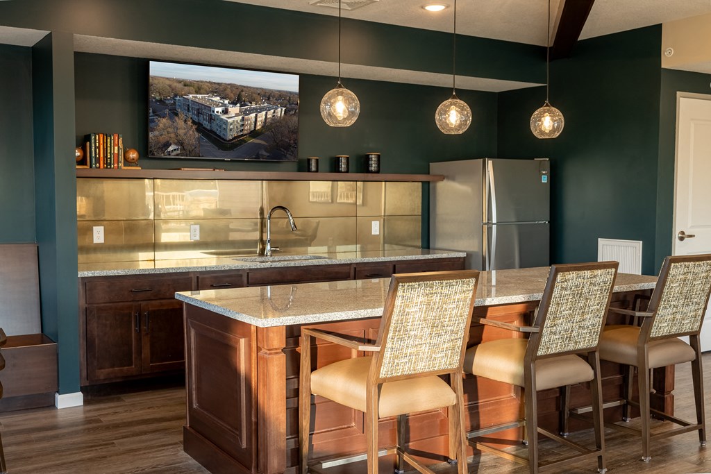 a kitchen with a bar and chairs and a refrigerator