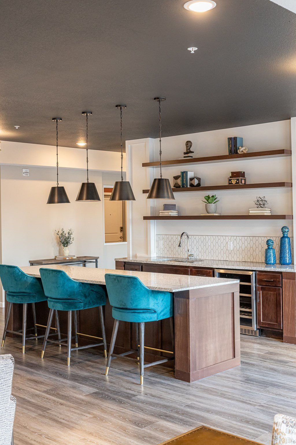 a kitchen with a bar and blue chairs in a house