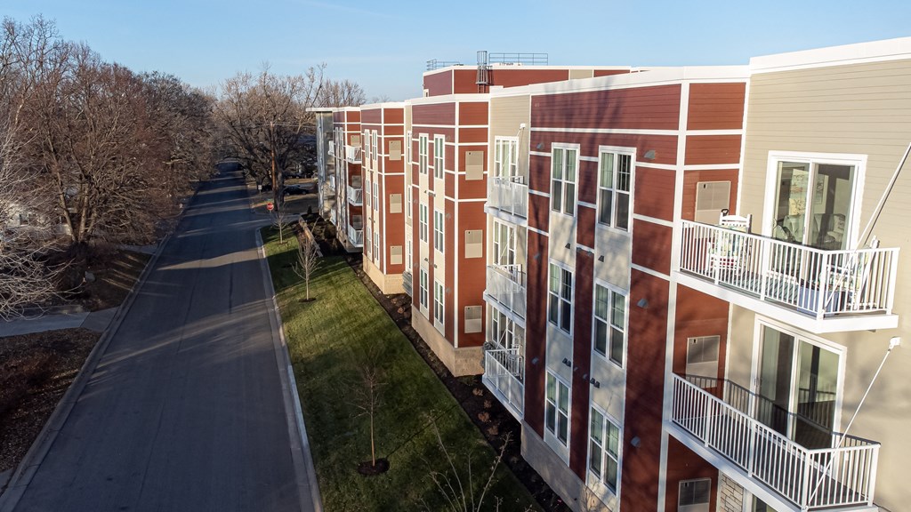a row of red and white buildings with balconies and a road