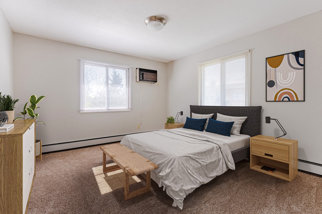 a bedroom with a bed and a dresser and two windows at Villa Del Coronado Apartments, Brooklyn Park, Minnesota