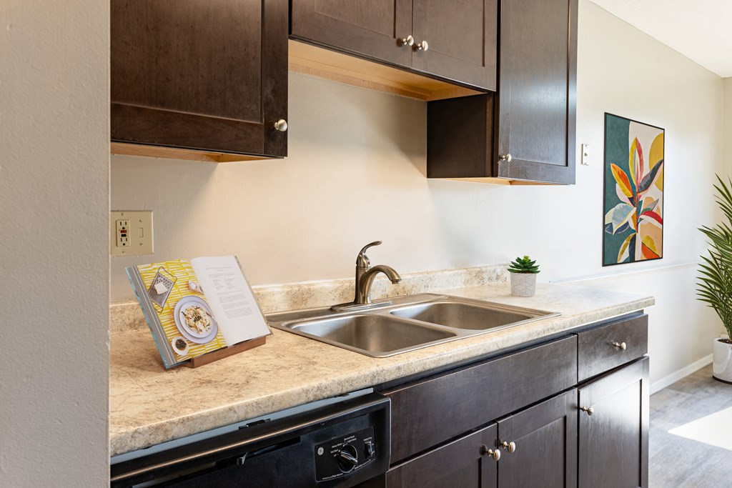 a kitchen with a sink and a book on the counter at Villa Del Coronado Apartments, Brooklyn Park, MN, 55443