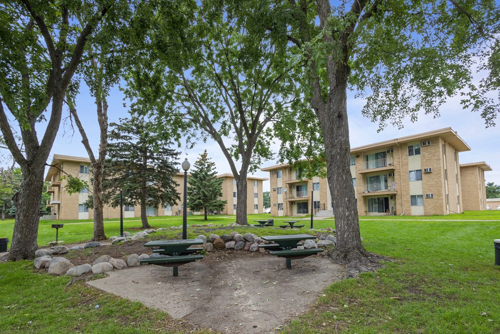 a park with picnic tables in front of an apartment building at Villa Del Coronado Apartments, Minnesota, 55443