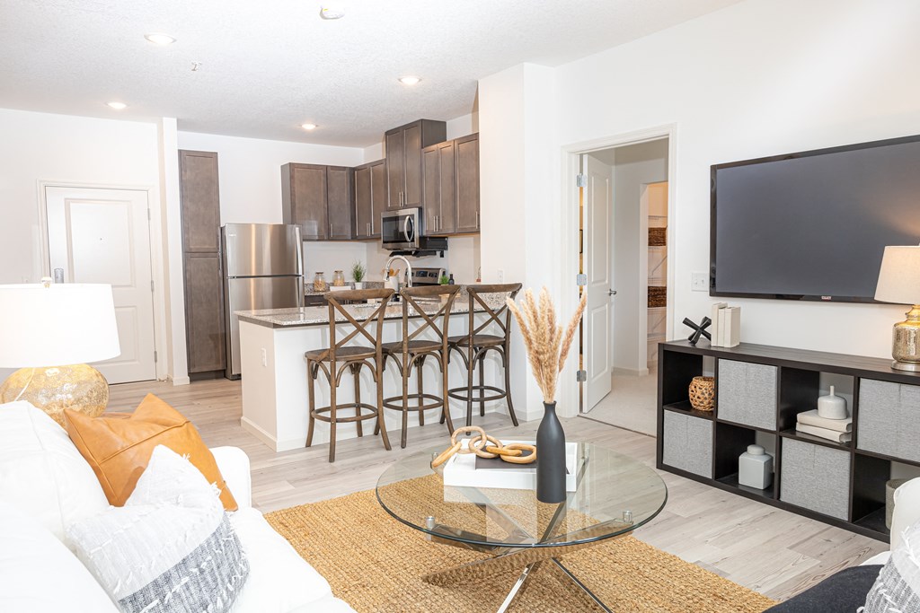 a living room with a kitchen with a bar and a television