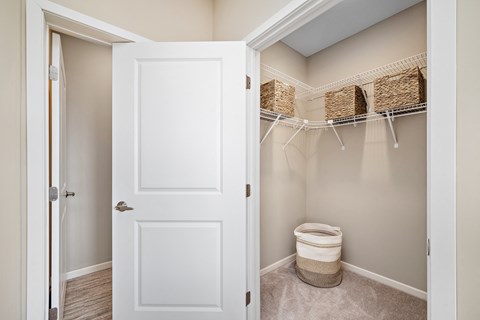 A white door is open to a bathroom with a toilet and storage baskets at The Winslow 62+ Apartments, Minnesota