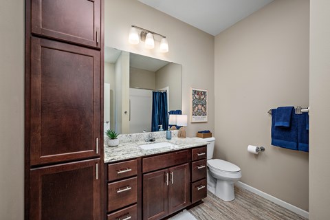 A bathroom with brown cabinets and a white toilet at The Winslow 62+ Apartments, Minnesota