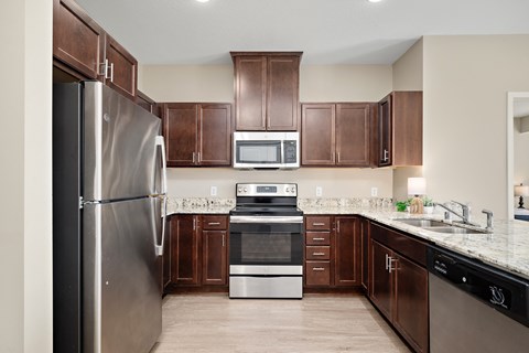 A kitchen with brown cabinets and a stainless steel refrigerator at The Winslow 62+ Apartments, West St Paul, 55118