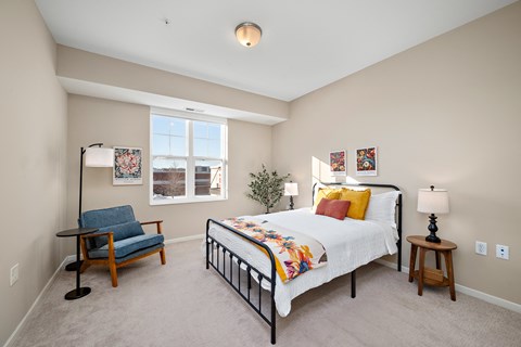 A bedroom with a bed, chair, and lamp at The Winslow 62+ Apartments, West St Paul, Minnesota