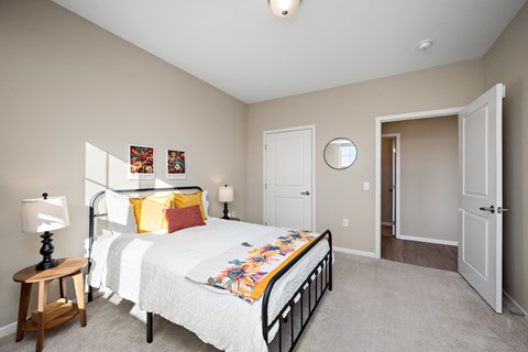 A bedroom with a bed, a nightstand, and a mirror at The Winslow 62+ Apartments, West St Paul, 55118