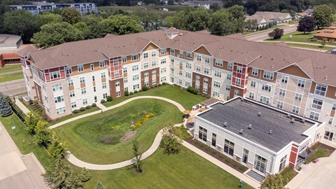 an aerial view of an apartment building with a green lawn and sidewalk at The Winslow 62+ Apartments, Minnesota