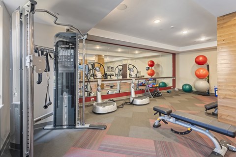 a gym with cardio equipment and weights on the floor at The Winslow 62+ Apartments, West St Paul, 55118