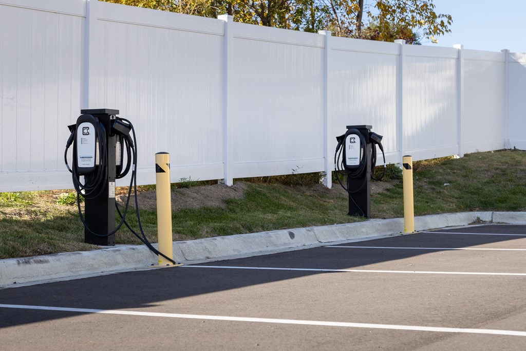 a row of electric parking meters in front of a white fence