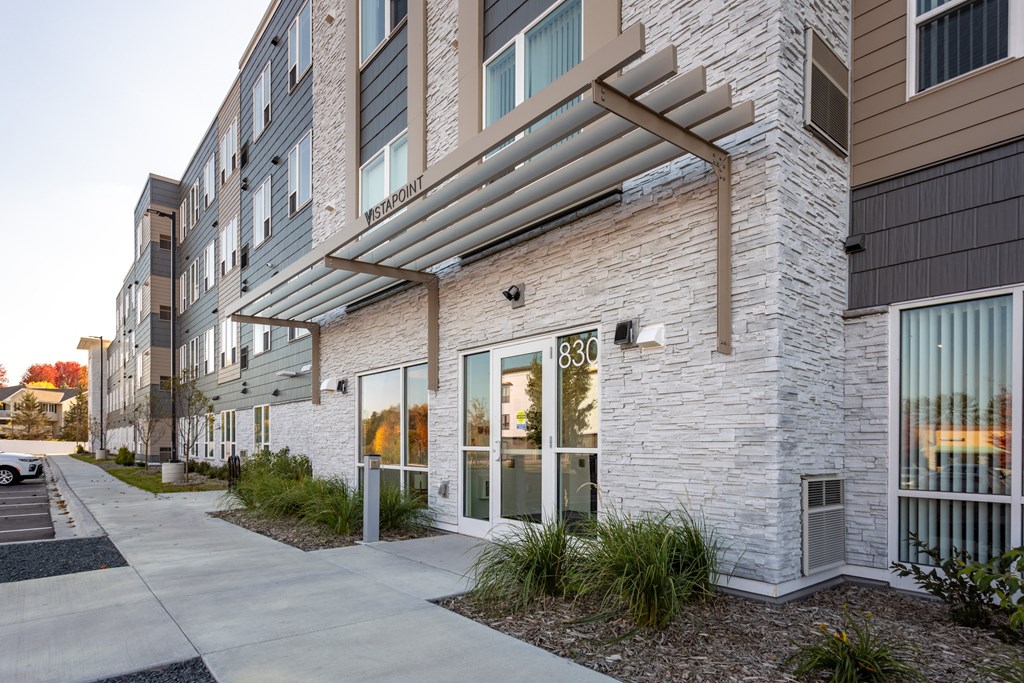 a brick building with large windows and a sidewalk