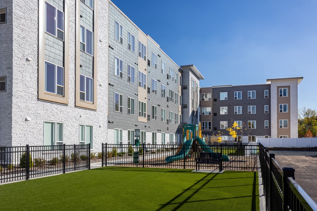 a playground in front of an apartment building with a play set