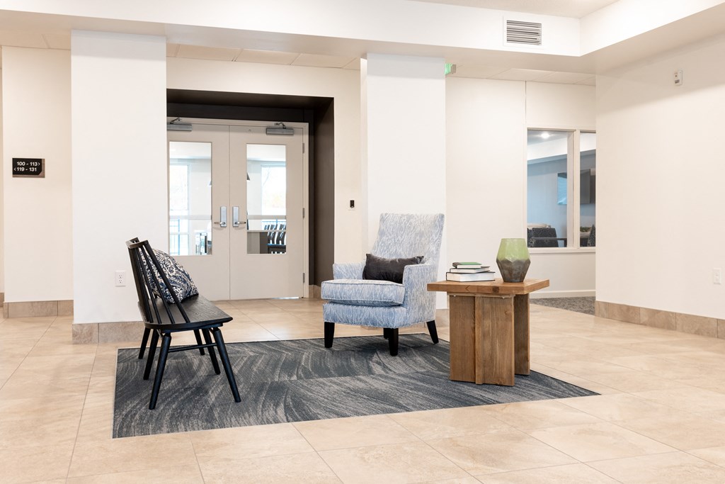 a lobby with chairs and a table in front of a door