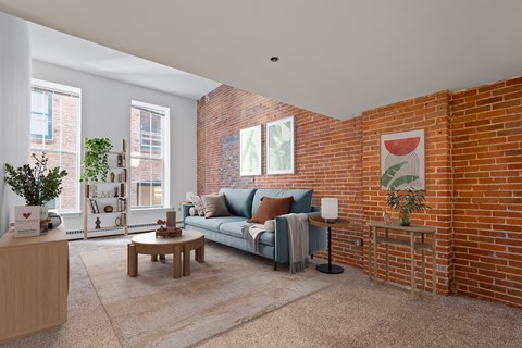 A living room with a blue couch and a brick wall.