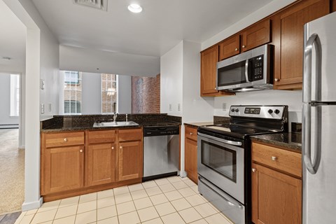 A kitchen with a black granite counter top and stainless steel appliances.