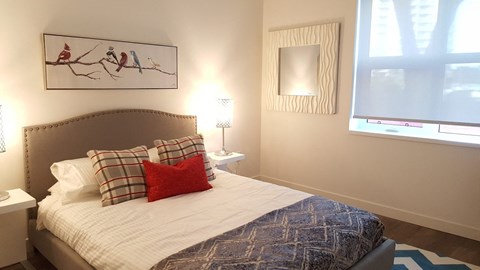 A bedroom with a bed, two lamps, and a painting on the wall.