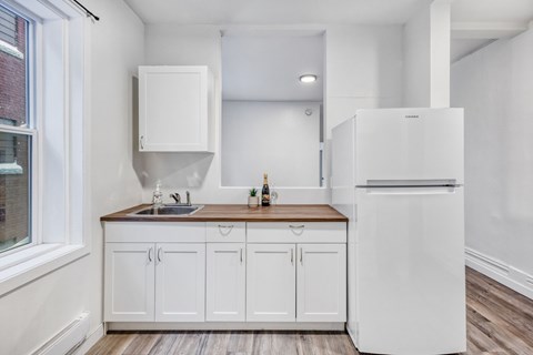 A white kitchen with a sink and a refrigerator.