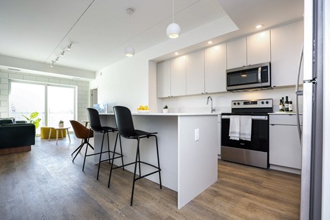 a kitchen with white cabinets and a bar with three stools