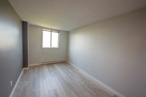 A room with a window and wooden flooring.