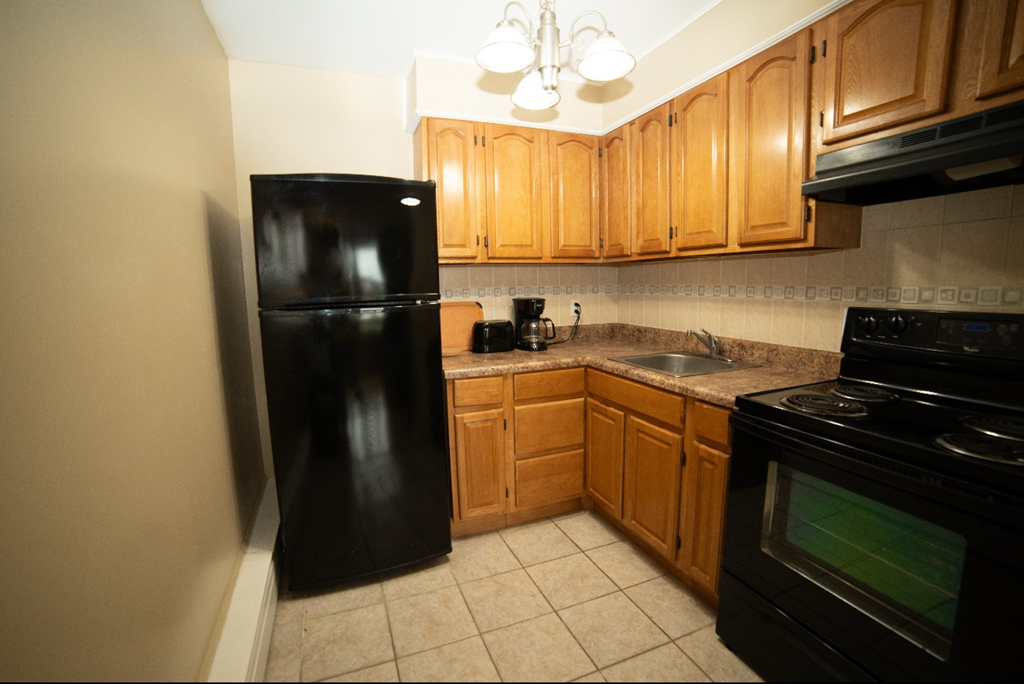 A kitchen with black appliances and wooden cabinets.