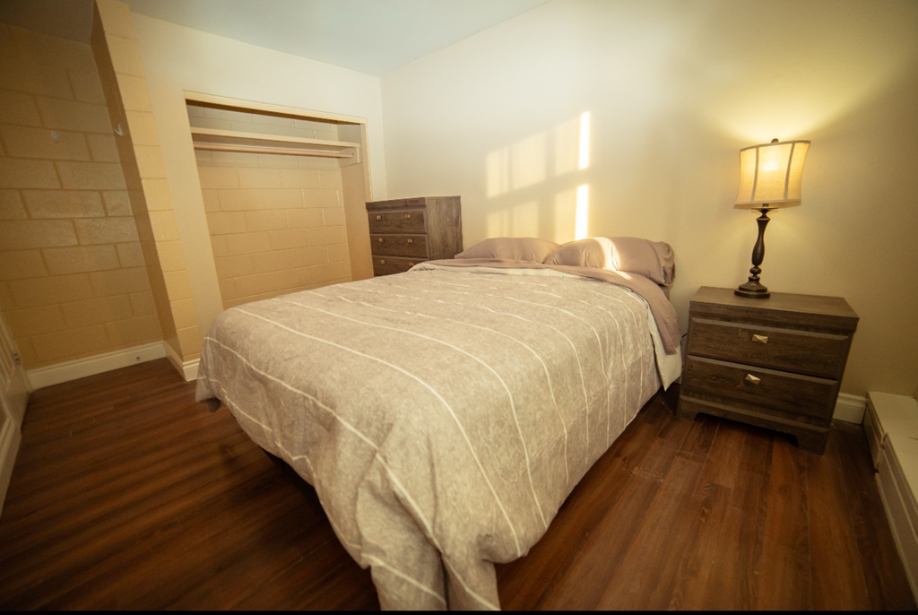 A bedroom with a bed, nightstand and lamp.