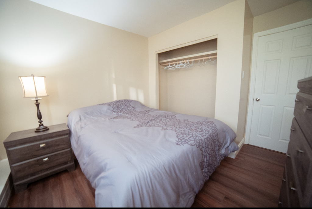 A bedroom with a bed, nightstand, and lamp.