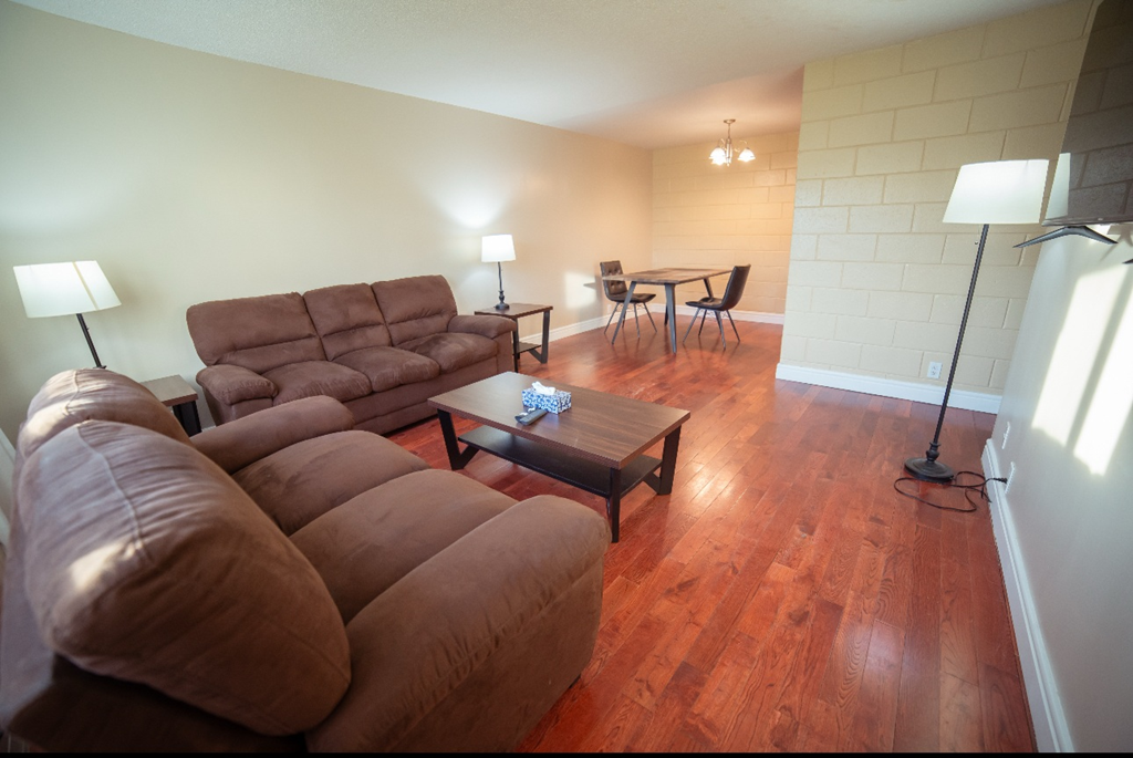 A living room with a brown couch and a wooden floor.