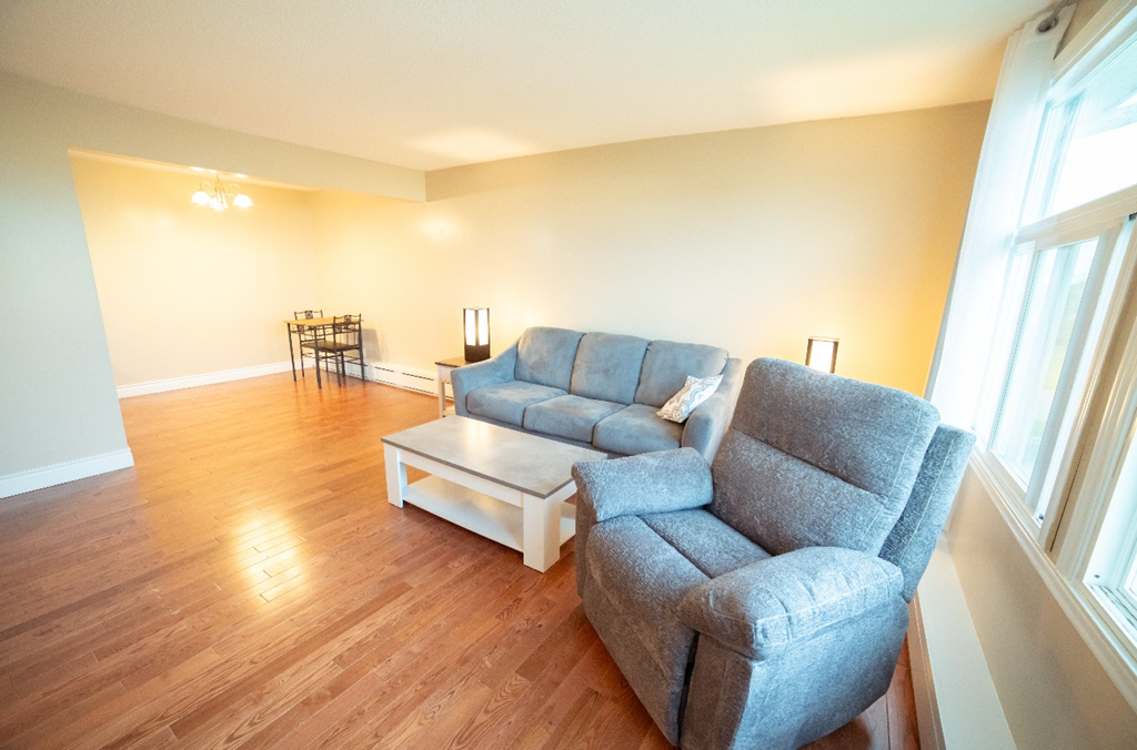 A grey couch and a white coffee table in a room with wooden flooring.