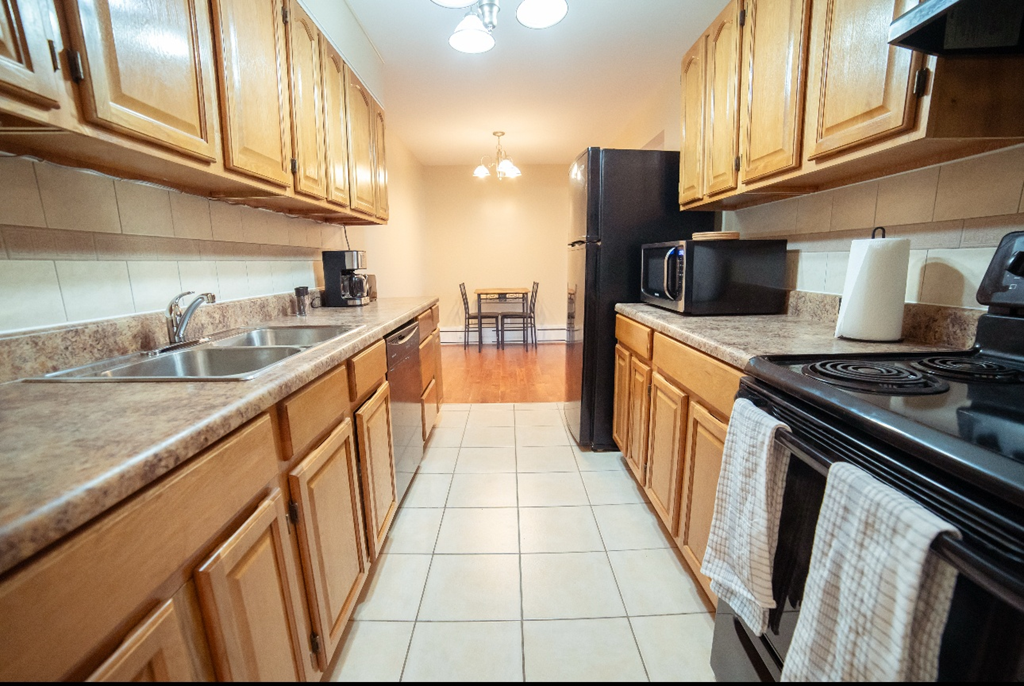 A kitchen with wooden cabinets and a black refrigerator.