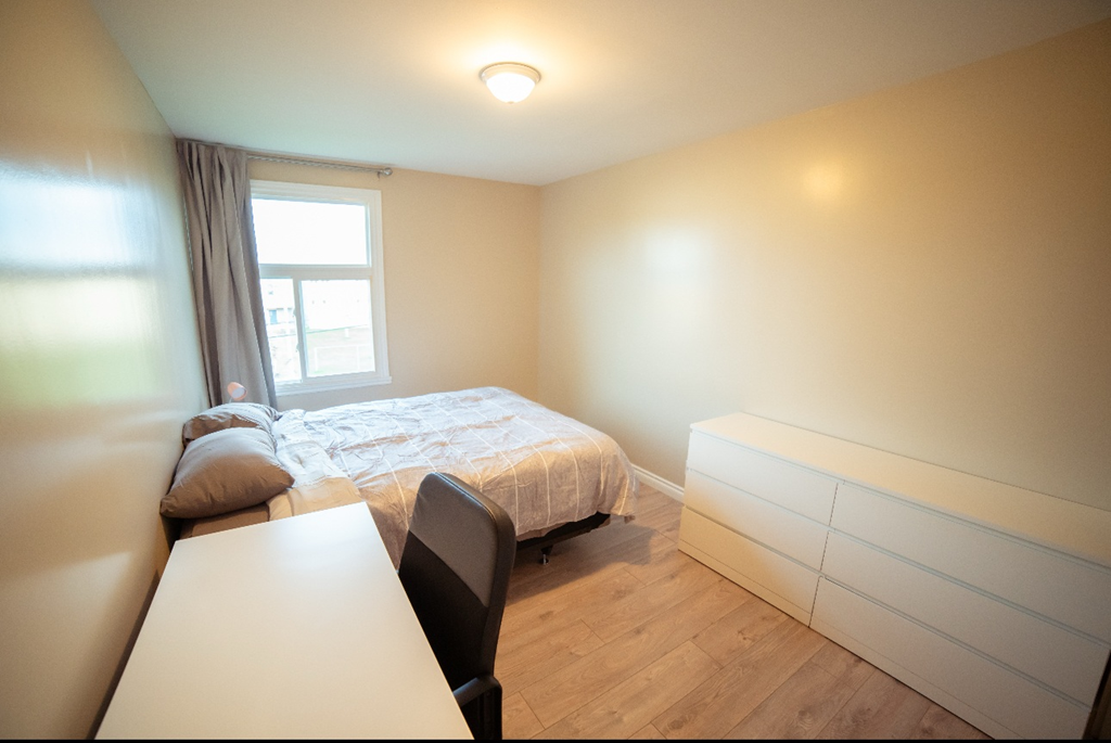 A bedroom with a bed, a table and a chair.