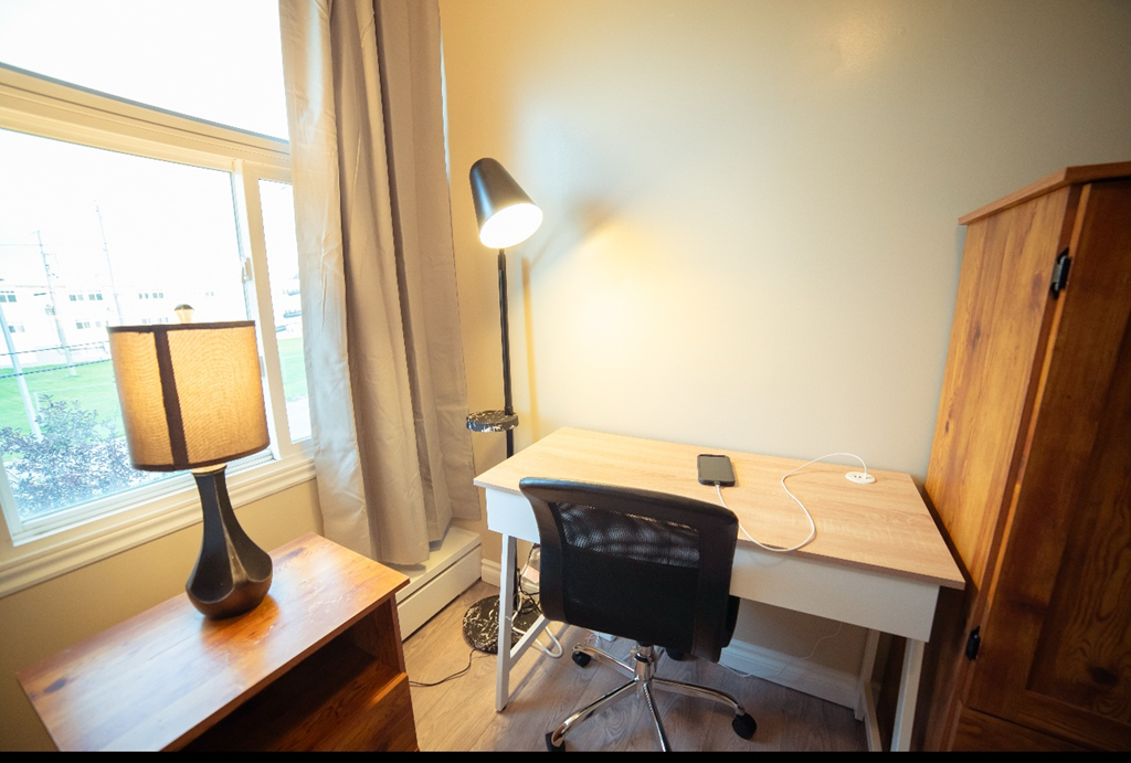 A desk with a chair and a lamp in a room.