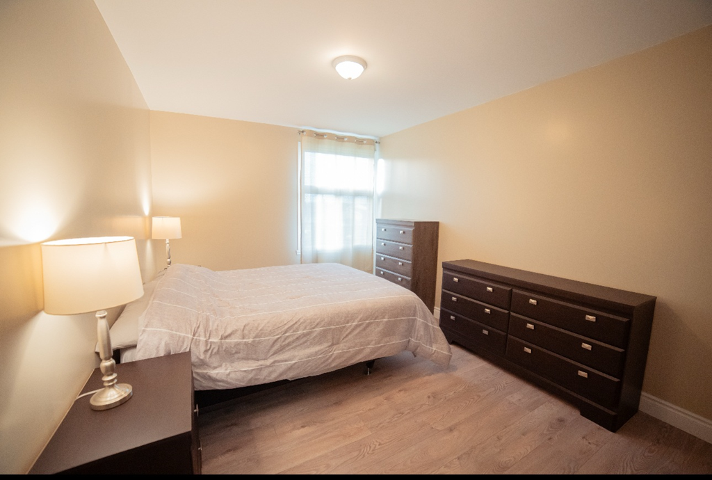 A bedroom with a bed, nightstand, and dresser.