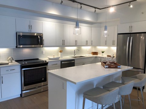 A modern kitchen with a white island and stainless steel appliances.