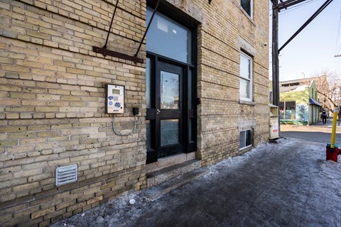A brick building with a black door and a sign on the wall.