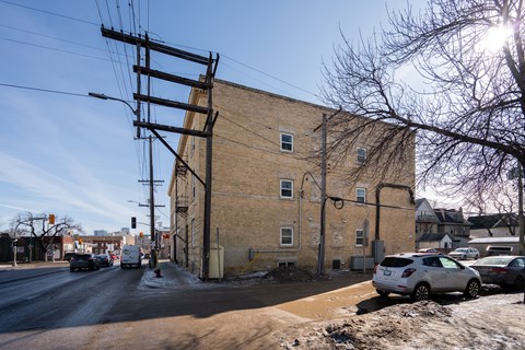 A street view with a car driving and a building on the side.