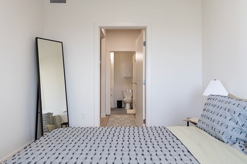 A bedroom with a large bed and a mirror on the wall.