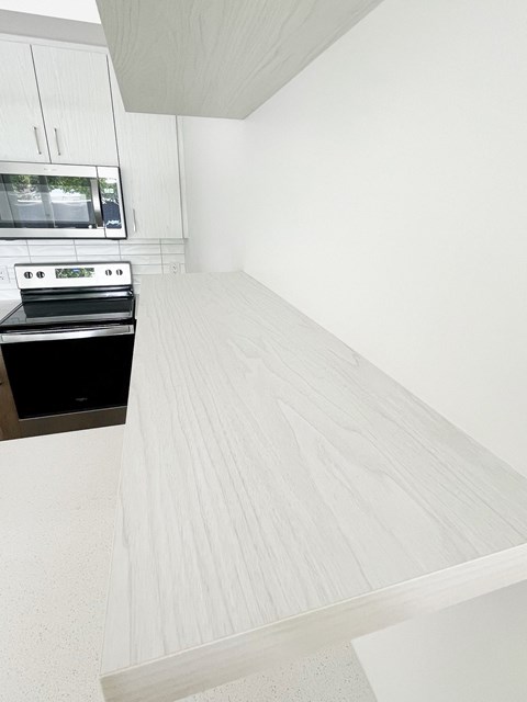a kitchen with a white counter top and a stove and a microwave