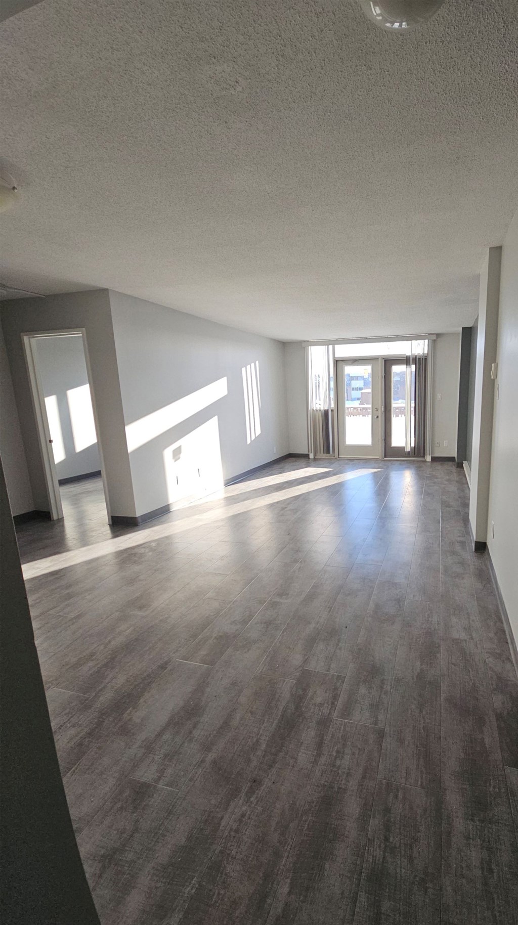 A room with wooden flooring and a doorway leading to another room.