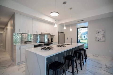 A kitchen with a white countertop and black bar stools.