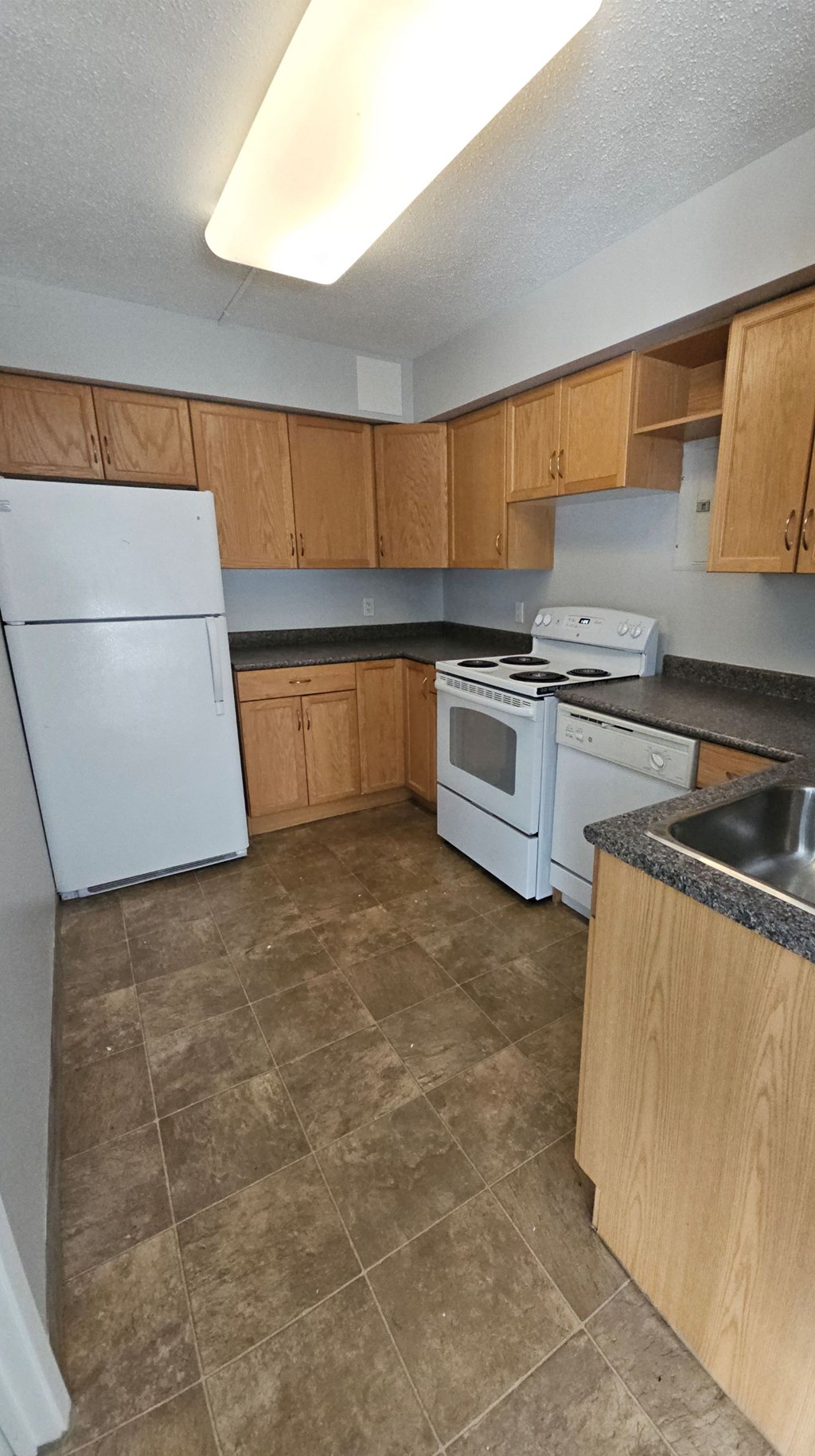 A kitchen with a white refrigerator, white stove, and wooden cabinets.