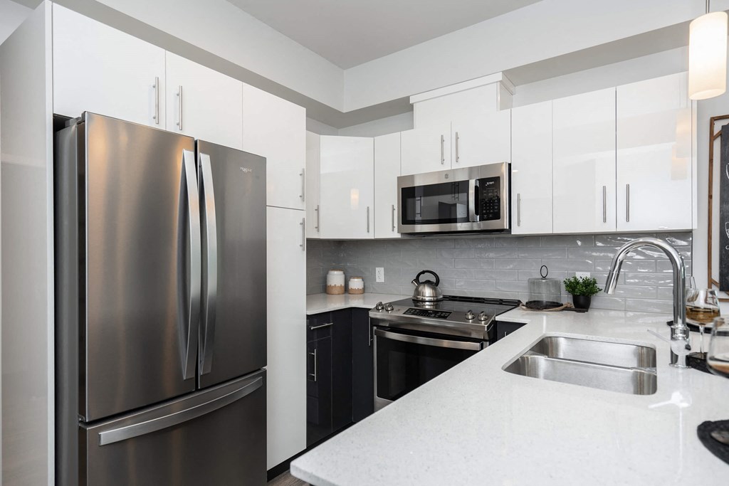 a modern kitchen with stainless steel appliances and white counter tops