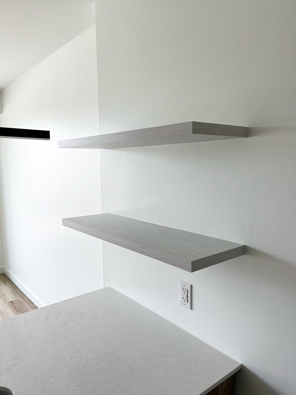 a living room with white walls and floating shelves