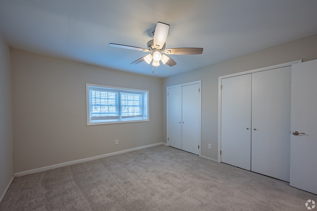an empty bedroom with a ceiling fan and a closet