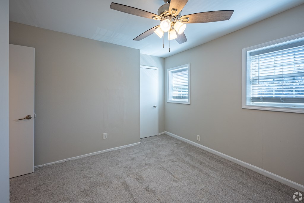 an empty bedroom with a ceiling fan and a window
