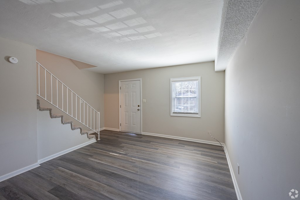 an empty living room with hardwood floors and a white door