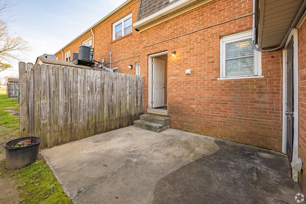 the back yard of a brick house with a wooden fence